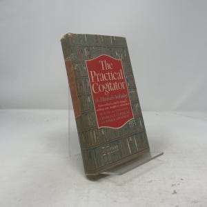 以下が含まれることがあります： 「The Practical Cogitator」というタイトルの本。赤と白のタイトルボックスが付いています。表紙は、緑と茶色の図書館をテーマにしたデザインです。本は透明なプラスチック製のスタンドに立てかけられています。本の寸法は不明です。