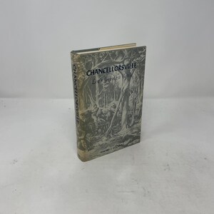 Könnte beinhalten: Ein gebundenes Buch mit dem Titel Chancellorsville: Lee's Greatest Battle von Edward J. Stackpole. Der Schutzumschlag zeigt eine schwarz-weiße Illustration von Soldaten zu Pferd in einem Wald mit dunklem Text auf hellgrauem Grund.