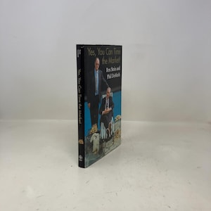 Può includere: Un libro intitolato "Yes, You Can Time the Market!" di Ben Stein e Phil DeMuth. La copertina presenta due uomini in giacca e cravatta, con il titolo e i nomi degli autori in testo bianco. Il dorso mostra anche il titolo.