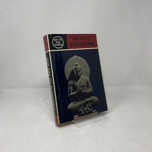 Puede incluir: Un libro de tapa dura titulado "The Art of Buddhism" con una cubierta azul oscuro que presenta una estatua de Buda sentado. El lomo del libro es rojo y el texto "The Art of Buddhism" es rojo. El libro forma parte de la serie "Art of the World".