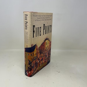 Op de afbeelding: Een hardcover boek met de titel "Five Points". De omslag toont een illustratie van een straatbeeld met gebouwen en mensen. De rug toont de titel en de naam van de auteur.