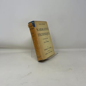 May include: A vintage book titled "Narrative Technique" by Thomas H. Uzzell. The book has a tan cover with black text and is propped up on a clear stand. The book's spine is blue.