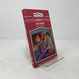 Könnte beinhalten: Ein Mills & Boon Liebesroman mit dem Titel Java Nights von Karen Van Der Zee. Das Buchcover hat einen roten Hintergrund mit einer Illustration von zwei Personen, die vor einem Kamin sitzen. Titel und Autor sind in weißem Text gedruckt.