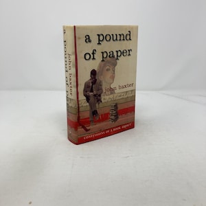 May include: A vintage paperback book titled "A Pound of Paper" by John Baxter. The cover features a sepia-toned illustration of a man and woman, with the words "Confessions of a Book Addict" at the bottom.