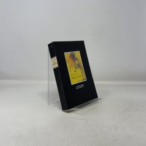 May include: A black book titled "Metamorphosen" by Paul Nizon, with a yellow and orange illustration on the cover. The book is displayed on a clear acrylic stand, with the spine visible.
