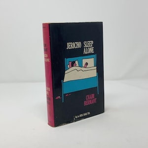 May include: A black book cover with the title "Jericho Sleep Alone" in white text. The cover features a simple illustration of a person sleeping in a blue bed with white sheets. The author's name, "Chaim Bermant", is printed in white text below the illustration. The book's spine is red with the title and author's name printed in white text.