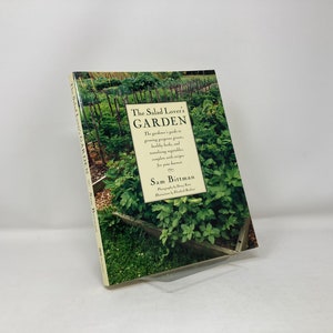 May include: A book titled "The Salad Lover's Garden" by Sam Bitman. The book cover features a photograph of a lush garden with various plants and vegetables.