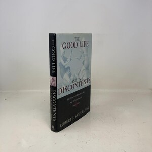 May include: A hardcover book titled "The Good Life and Its Discontents" by Robert J. Samuelson. The book has a black spine with white text and a cover featuring a grayscale image of people. The book's title is in large, bold letters.