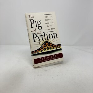 Peut inclure: Un livre intitulé "The Pig and the Python" avec le sous-titre "How to Prosper from the Aging Baby Boom". La couverture présente un motif de montagne stylisé avec un motif de soleil. Le nom de l'auteur, David Cork, est également visible.