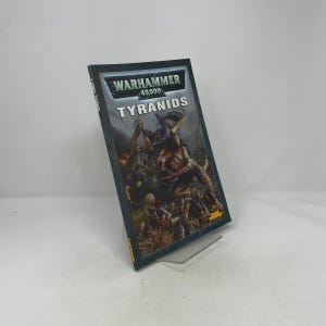 May include: A Warhammer 40,000 Tyranids book. The cover features a dark, detailed illustration of alien creatures in shades of brown, green, and gray. The title is in white and the Warhammer logo is at the top.