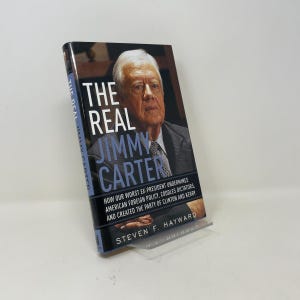 May include: A hardback book titled The Real Jimmy Carter by Steven F. Hayward. The cover features a portrait of Jimmy Carter in a grey suit and tie. The subtitle reads: How Our Worst Ex-President Undermines American Foreign Policy, Coddles Dictators, and Created the Party of Clinton and Kerry.