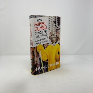 May include: A book titled "How Mumbo-Jumbo Conquered the World: A Short History of Modern Delusions" by Francis Wheen. The cover shows a crowd of people and a person in a yellow duck costume.