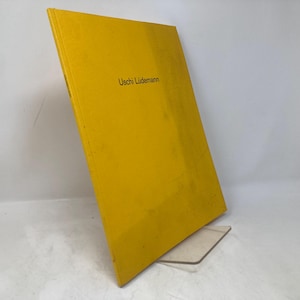 Pode incluir: Um livro amarelo com o título "Uschi Lüdemann" impresso na capa.