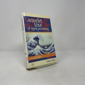 May include: A hardcover textbook titled A Wavelet Tour of Signal Processing by Stéphane Mallat, Second Edition. The cover features a reproduction of The Great Wave off Kanagawa in blue and white, with orange accents and white text on a cream background.