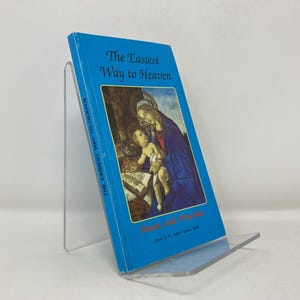 以下が含まれることがあります： 透明なアクリルスタンドに飾られた、タイトル「The Easiest Way to Heaven」の青い本。表紙には女性と子供のイラストが描かれています。本の背表紙には「The Easiest Way to Heaven」と書かれています。