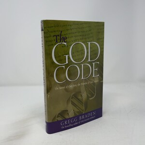 May include: A book titled The God Code by Gregg Braden with a green cover featuring a DNA double helix graphic and ancient text. The subtitle reads The Secret of Our Past, the Promise of Our Future. The bottom section is a solid purple band.