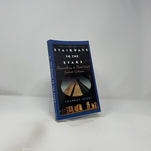 Puede incluir: Un libro de tapa dura titulado "STAIRWAYS TO THE STARS" con una cubierta azul. La portada del libro presenta el título en blanco, con el subtítulo "Skywatching in Three Great Ancient Cultures". El nombre del autor, Anthony Aveni, también es visible.