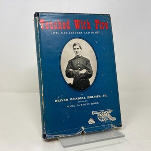 May include: A blue book titled "Touched With Fire: Civil War Letters and Diary of Oliver Wendell Holmes, Jr. Edited by Mark De Wolfe Howe". The cover features a black and white portrait of a man in a military uniform.