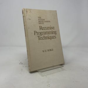 Può includere: Un libro con copertina rigida intitolato Recursive Programming Techniques di W.H. Burge, parte della serie The Systems Programming Series. Il libro presenta una copertina beige chiaro con testo marrone scuro. Il dorso è visibile, mostrando titolo e autore.