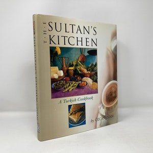May include: The Sultan's Kitchen: A Turkish Cookbook by Ozcan Ozan. The cover features a colorful still life of Turkish food, including a bowl of green beans, a plate of olives, a loaf of bread, and a cup of coffee.