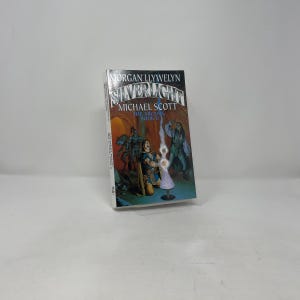 May include: A paperback book titled "Silverlight" by Morgan Llywelyn and Michael Scott. The cover art features a fantasy scene with figures and a glowing light. The book is the second in "The Arcana" series.