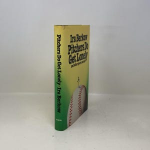May include: A hardcover book titled "Pitchers Do Get Lonely" by Ira Berkow. The book has a yellow and green cover with a baseball illustration. The title is in bold, dark green letters, and the author's name is also visible.