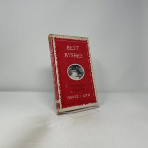 May include: A vintage book titled "Best Wishes" with a red cover and white text. The cover features a circular illustration and the author's name, Harold E. Kohn. The book is slightly angled, showcasing its spine and cover details.