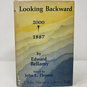 May include: A vintage paperback book titled "Looking Backward" by Edward Bellamy. The cover features a gradient design in yellow, blue, and white, with the years 2000 and 1887 prominently displayed. Edited by John L. Thomas, it's a John Harvard Library Book.