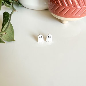 May include: A pair of white ghost-shaped earrings with black eyes.