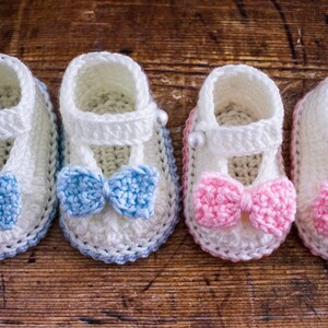 May include: Four pairs of crocheted baby booties with bows. Two pairs have blue bows and two pairs have pink bows.