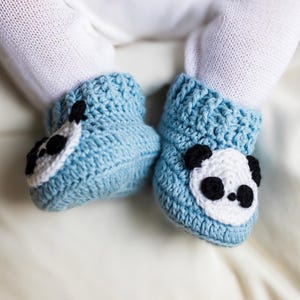 Può includere: Un paio di scarpine per neonati in crochet blu con facce di panda. Le scarpine sono realizzate con un filato morbido e testurizzato e hanno un design carino e fantasioso.
