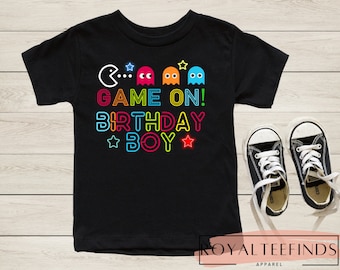 Puede incluir: Camiseta negra con un gráfico de neón de fantasmas de Pac-Man y el texto "Game On! Birthday Boy".