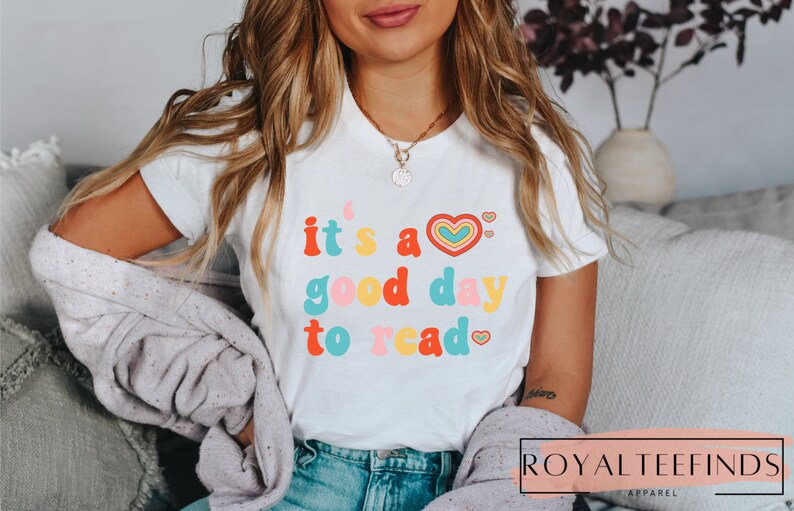 K&ouml;nnte beinhalten: Wei&szlig;es T-Shirt mit dem Text "it's a good day to read" in bunter Retro-Schrift mit Herzen.