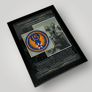 Peut inclure: Une présentation encadrée d'un patch d'uniforme de pilote de la 15e Force aérienne de la Seconde Guerre mondiale. Le patch est bleu avec un motif d'aile jaune et une étoile rouge. Le texte "A Piece of Air Force History" et une description du rôle de la 15e Force aérienne pendant la Seconde Guerre mondiale sont imprimés sous le patch.