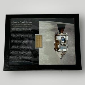 Könnte beinhalten: Eine schwarze gerahmte Anzeige mit einem Stück NASA-Geschichte, einem Bauplan des Apollo 16 Command and Service Module (CSM)-Raumschiffs. Der Text lautet "A Piece of NASA History, Apollo 16 Command and Service Module (CSM) Spacecraft NASA Blueprint".