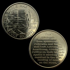 Puede incluir: Una moneda de plata con una imagen de un astronauta plantando una bandera en la luna. El texto "The Eagle Has Landed" está inscrito alrededor del borde de la moneda. El otro lado de la moneda tiene texto que dice "This Medallion contains metal from spacecrafts Columbia and Eagle that took Astronauts Armstrong, Aldrin and Collins on their historic Apollo 11 mission that resulted in the first landing of man on the Moon."
