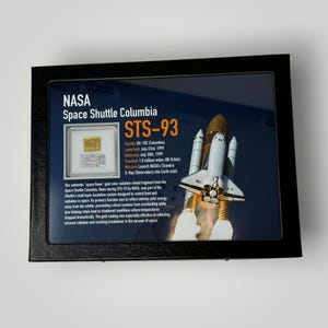 May include: Framed display featuring a gold solar radiation shield fragment from the Space Shuttle Columbia STS-93 mission. The display includes text detailing the mission, launch date, and distance traveled. A detailed description is also included.