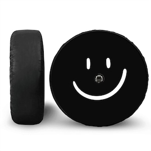 K&ouml;nnte beinhalten: Schwarze Reifenabdeckung mit einem wei&szlig;en Smiley-Gesicht.