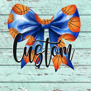 Puede incluir: Un lazo azul con balones de baloncesto impresos en él. El lazo está atado con un nudo en el centro y la palabra "Custom" está escrita en negro debajo del lazo.