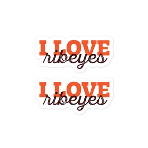 May include: Two orange and white stickers with the text "I LOVE ribeyes" in black lettering.