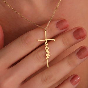 May include: Gold necklace with a cross pendant that has the word "Faith" written vertically down the cross.