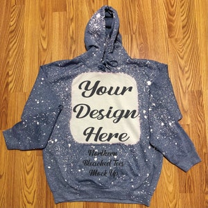 Puede incluir: Una sudadera con capucha azul con un dise&ntilde;o blanqueado y el texto "Your Design Here". La sudadera tiene una capucha con cord&oacute;n y un bolsillo delantero. Tambi&eacute;n se ve el texto "Northern Bleached Tees Mock Up".