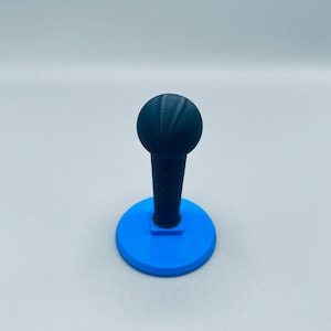 Peut inclure: Un joystick imprimé en 3D noir avec un sommet rond et une base bleue.