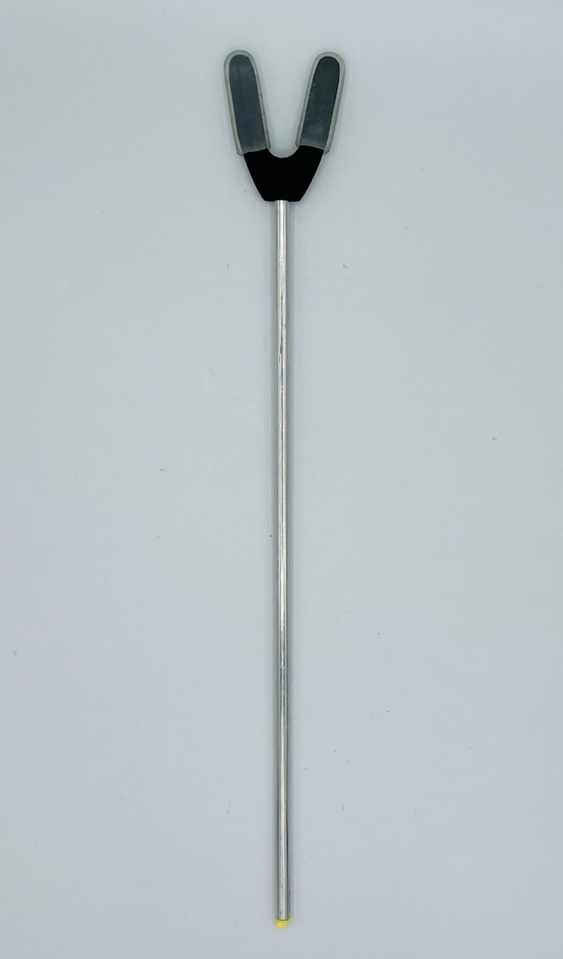 May include: A silver metal tool with a black rubber V-shaped tip. The tool is used for holding open a patient's mouth during a medical procedure.