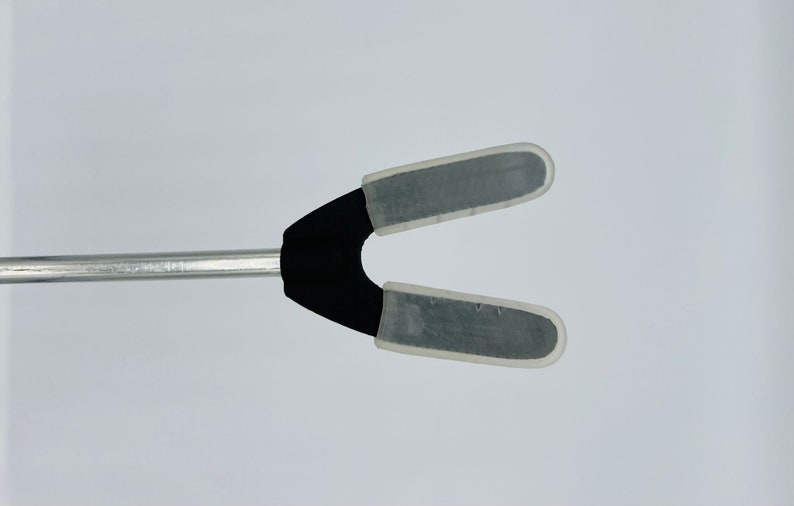 May include: A black and silver tool with two clear plastic tips. The tool is attached to a silver metal rod.