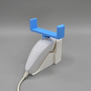 以下が含まれることがあります： 白い任天堂Wiiリモコンが、白いスタンドに装着されています。スマートフォンまたはタブレット用の薄い青色のプラスチックスタンドが付いています。