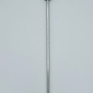 May include: A silver metal tongue depressor with a black rubber tip and two gray rubber flaps at the top.