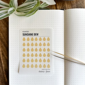 May include: A sheet of clear stickers with a yellow raindrop design. The stickers are labeled "SUNSHINE DEW" and "essentials". The sheet also includes the text "made in the US by dainty favors".