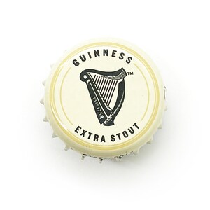 May include: A white bottle cap with a black Guinness logo, featuring a harp and the text "GUINNESS ESTD 1759 EXTRA STOUT TM".