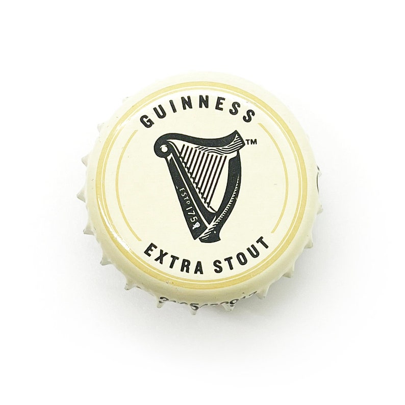 May include: A white bottle cap with a black Guinness logo, featuring a harp and the text "GUINNESS ESTD 1759 EXTRA STOUT TM".